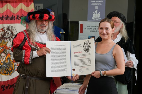 Der Gautschmeister überreicht der nun ehemaligen und sichtlich stolzen Kornutin den aufwendig gestalteten Gautschbrief. 