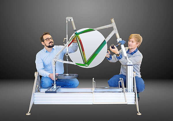 Bikelab Kjell Bühler (links) und Felix Kaule hocken neben einem Fahrradrahmen und messen