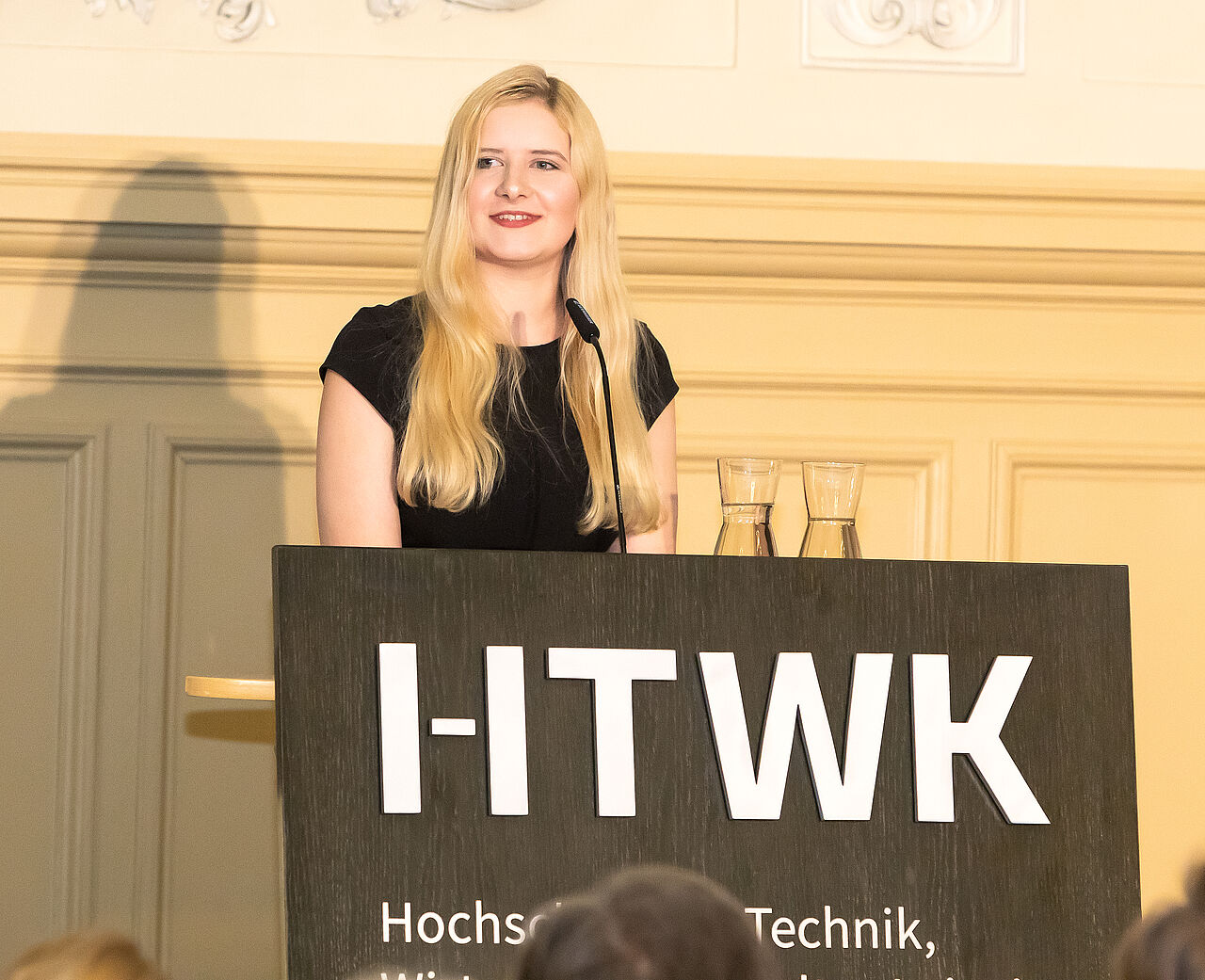 StuRa-Sprecherin Sabine Giese hält eine Rede an einem HTWK-Rednerpult zur Feierlichen Investitur des neuen Rektors im November im Salles de Pologne Leipzig